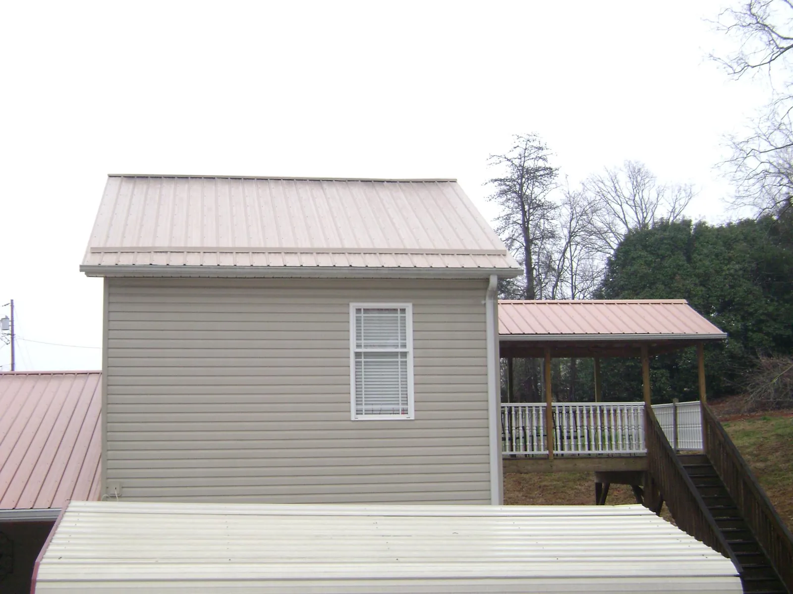 Tan metal roofs on a two story addition and attached porch, from a Roof Replacement job in Lakeland